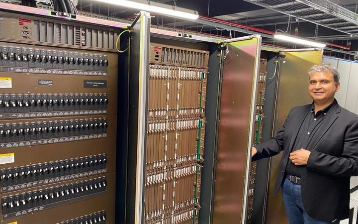 Colt's VP of Engineering, Vivek Gaur, standing next to racks of old networking equipment