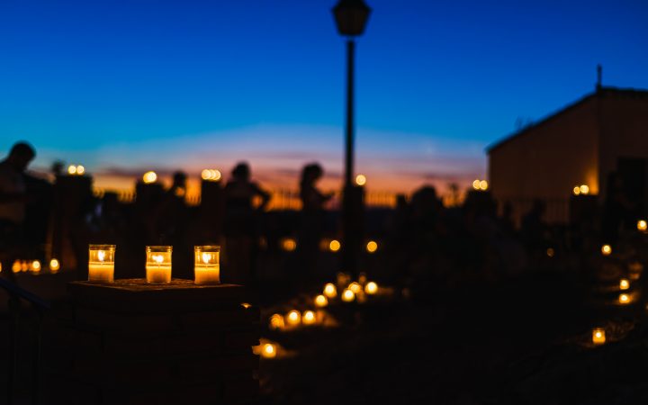 A blurry scene showing people and buildings lit by candles