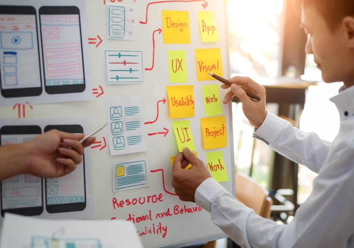 UX designer creative group working about planing mobile application project with sticky notes. User experience concept.